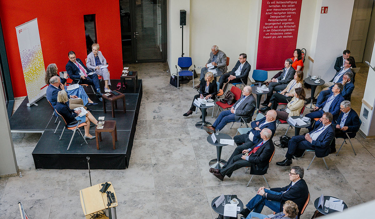 Auf der linken Seite des Bildes ist aus der Vogelperspektive das Panel sehen und rechts die Teilnehmenden